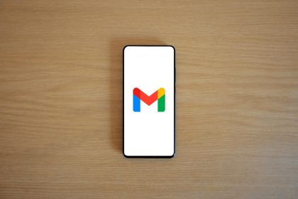 A smartphone displaying the Gmail app logo on a wooden surface, viewed from above.
