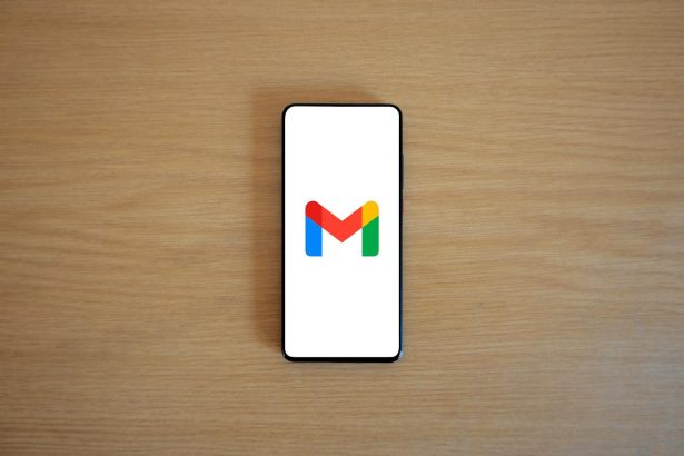 A smartphone displaying the Gmail app logo on a wooden surface, viewed from above.
