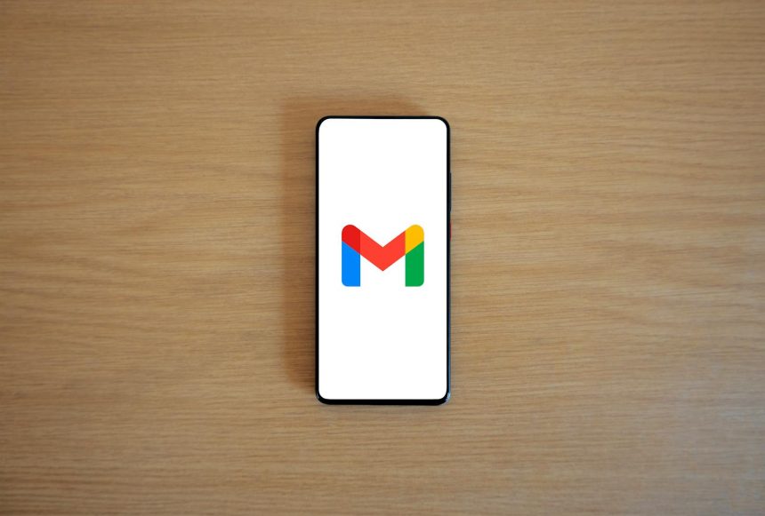 A smartphone displaying the Gmail app logo on a wooden surface, viewed from above.