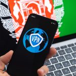 VPN w Afganistanie Koncepcja bezpiecznego i bezpiecznego internetu Prywatność Ręka z telefonem komórkowym i aplikacją VPN Flaga i laptop na zdjęciu w tle