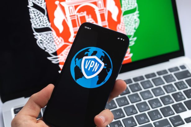 VPN w Afganistanie Koncepcja bezpiecznego i bezpiecznego internetu Prywatność Ręka z telefonem komórkowym i aplikacją VPN Flaga i laptop na zdjęciu w tle