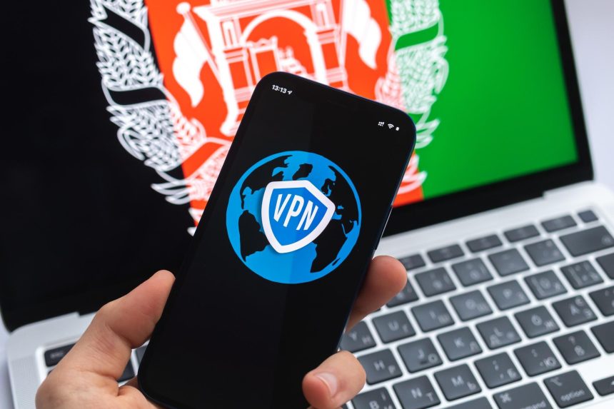 VPN w Afganistanie Koncepcja bezpiecznego i bezpiecznego internetu Prywatność Ręka z telefonem komórkowym i aplikacją VPN Flaga i laptop na zdjęciu w tle