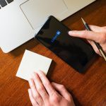 Dłoń dotykająca smartfona z aplikacją linkedin na biurku