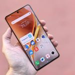 A person holding a smartphone displaying various apps on a pink background. Ideal for technology themes.