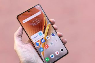 A person holding a smartphone displaying various apps on a pink background. Ideal for technology themes.