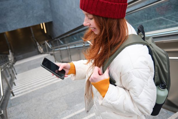 Uśmiechnięta dziewczyna chodząca po schodach za pomocą wiadomości tekstowej z telefonu komórkowego po drodze za pomocą aplikacji na smartfona ma