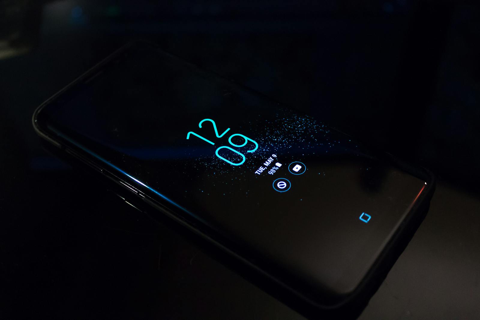 Close-up of a smartphone in the dark displaying digital clock and notifications.