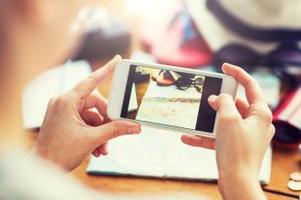 koncepcja wakacji, turystyki, podróży, technologii i ludzi - zbliżenie kobiety ze smartfonem fotografującej mapę i rzeczy podróżne