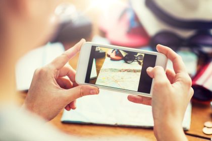 koncepcja wakacji, turystyki, podróży, technologii i ludzi - zbliżenie kobiety ze smartfonem fotografującej mapę i rzeczy podróżne