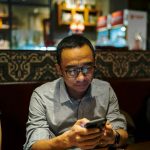 Man is looking at his phone in a restaurant.