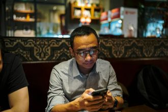Man is looking at his phone in a restaurant.
