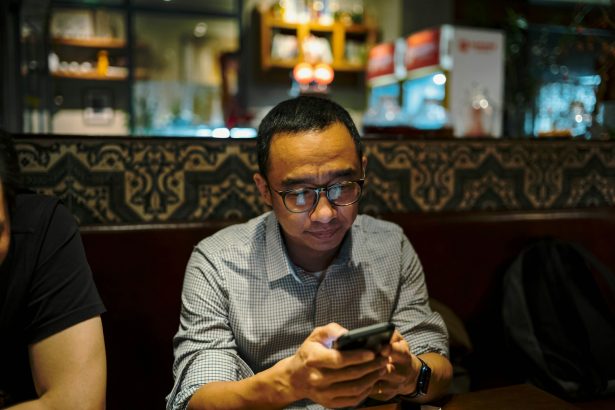 Man is looking at his phone in a restaurant.