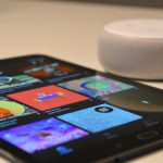 black tablet computer beside round white portable speaker