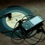 in-ear headphones plugged in black Sony Walkman on vinyl record