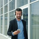 Man in suit listening to music on headphones outside