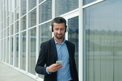Man in suit listening to music on headphones outside