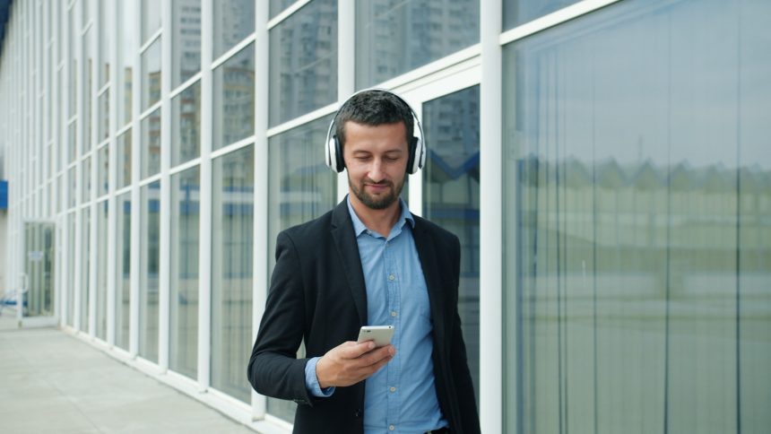 Man in suit listening to music on headphones outside