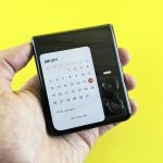 A hand holds a phone displaying a calendar.