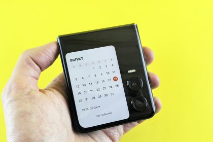 A hand holds a phone displaying a calendar.