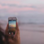 person taking a photo of of open sea and sunset