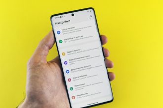 A hand holds a phone with settings displayed.
