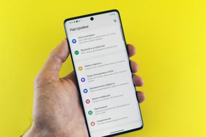 A hand holds a phone with settings displayed.