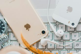 gold iPhone 7 beside white Apple EarPods and silver iPhone 5s