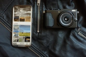 Smartphone and camera on black leather