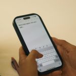 Hands typing on a smartphone with a message on screen.