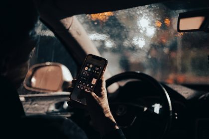 a person sitting in a car holding a cell phone